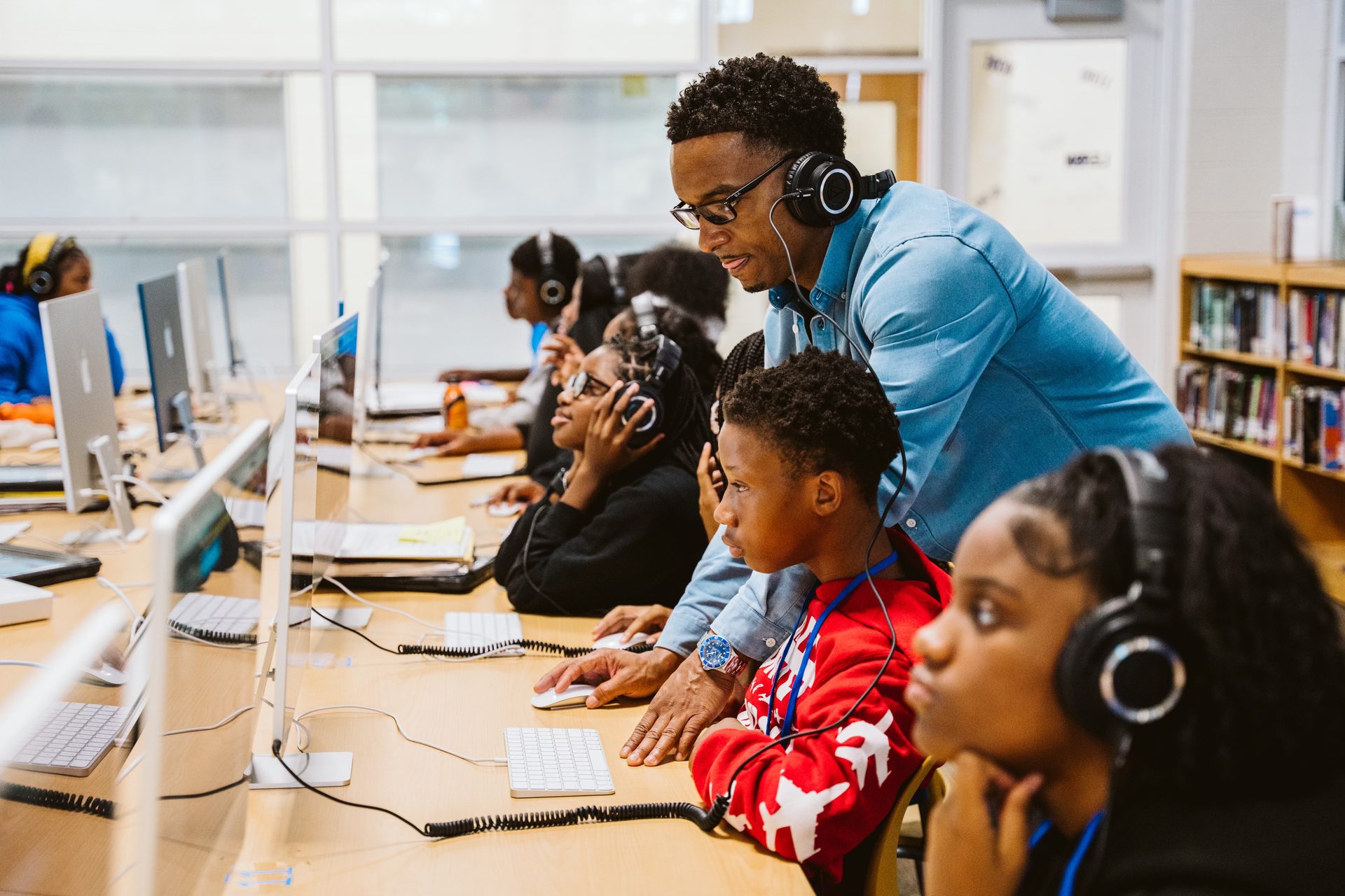 Keyz Bridgez guiding a student wearing headphones at a computer